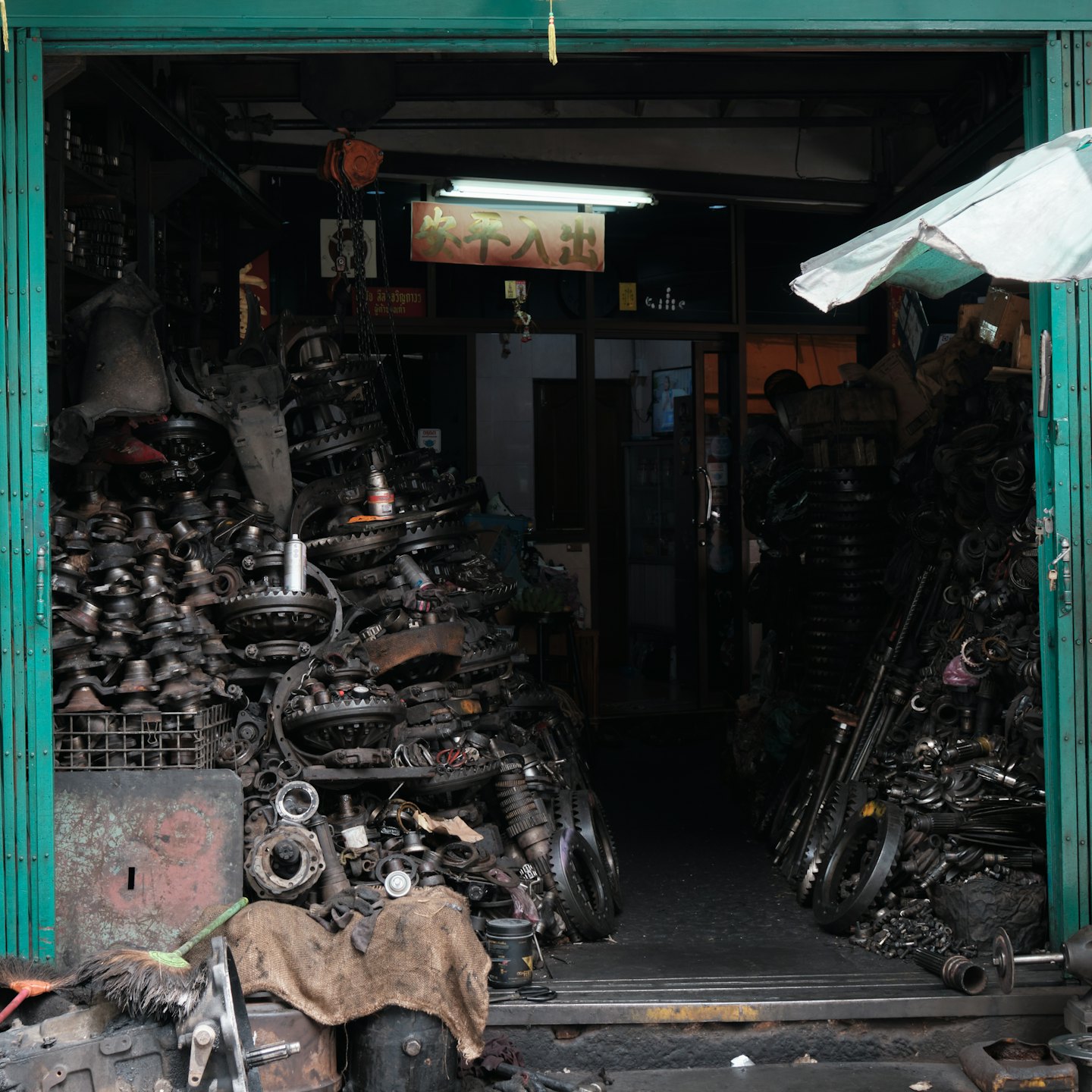 Cluttered auto parts shop interior with piles of engine components.