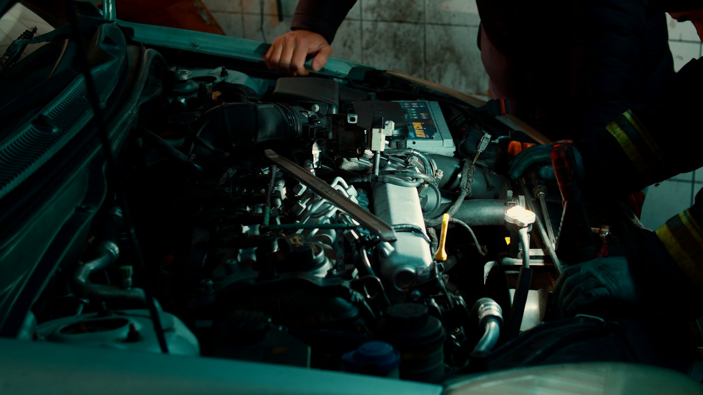 Mechanic's hands working on a car engine in a garage.